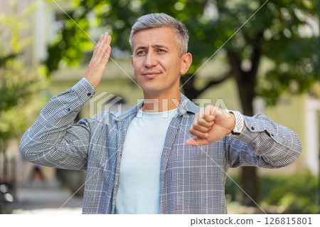 Mature man looking at wristwatch while waiting for someone feeling upset about being late in city 126815801