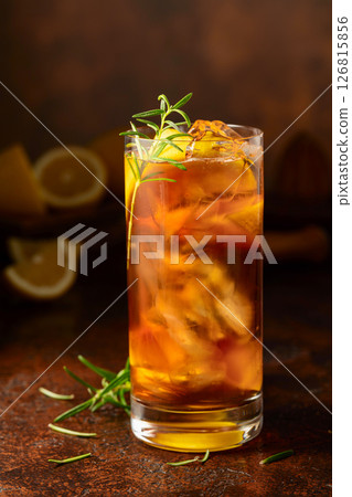 Iced tea or cocktail with ice, rosemary and lemon slices on the old brown table. 126815856