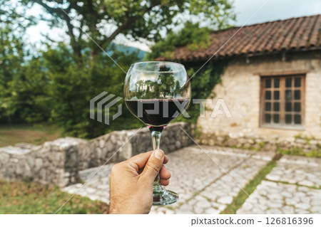Red Wine Glass in Hand with Stone Cellar Background in France or Italy 126816396