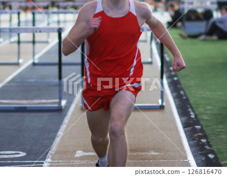 Runner Competes in Hurdles Event on an Indoor Track at Athletic Competition 126816470
