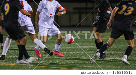 Exciting Soccer Match Highlights Competitive Youth Players in Action at Night 126816512