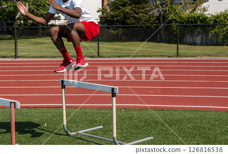 Young Athlete Jumps Over Hurdles Turf Field During Training 126816538