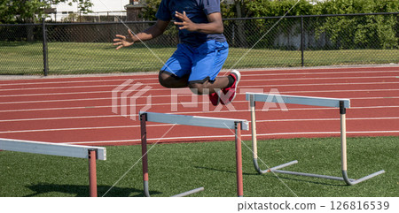 Young Athlete Practices Jumping Over Hurdles on Training Track Young Athlete Practices Jumping Over Hurdles on Training Track 126816539
