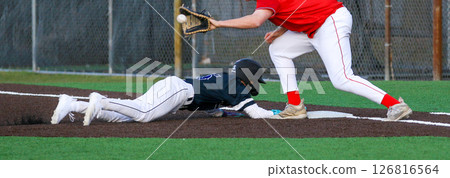 Base Runner Attempts to Slide Back to First Base During Youth Baseball Game 126816564