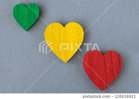 Traffic light colors wood hearts on the gray fabric background. Romantic greeting card. Traffic light colors wood hearts on the gray fabric background. Romantic greeting card. 126816921