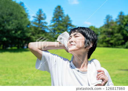 Middle-aged woman wiping sweat after exercise in the park Middle-aged woman wiping sweat after exercise in the park 126817860