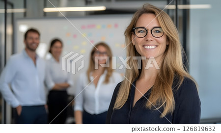 Friendly team brainstorming in creative office space whiteboard behind sticky notes on glass 126819632