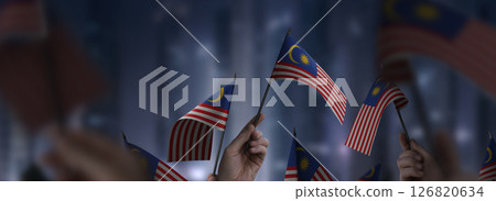 Malaysia flags in their hands on a blurred urban background 126820634