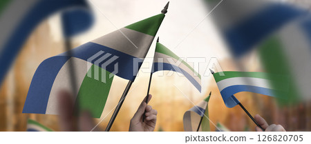Sierra Leone flags in their hands on a blurred urban background 126820705