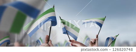 Sierra Leone flags in their hands on a blurred urban background Sierra Leone flags in their hands on a blurred urban background 126820748