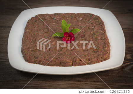Delicious Lebanese Kebbe Naye garnished with olive oil and fresh mint on a rustic wooden table Delicious Lebanese Kebbe Naye garnished with olive oil and fresh mint on a rustic wooden table 126821325