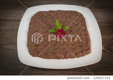 Delicious Lebanese Kebbe Naye garnished with olive oil and fresh mint on a rustic wooden table Delicious Lebanese Kebbe Naye garnished with olive oil and fresh mint on a rustic wooden table 126821332