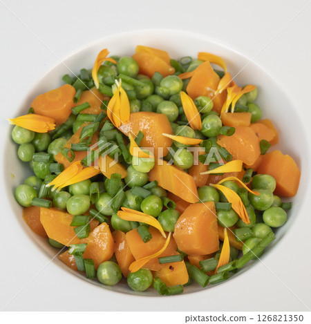 Fresh garden peas and carrots cooked in butter, garnished with chives and marigold flowers for a Fresh garden peas and carrots cooked in butter, garnished with chives and marigold flowers for a 126821350