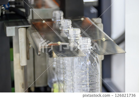 The drinking water bottles on the conveyor belt after blow mold machine. 126821736