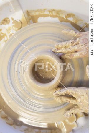 Close-up of a potter's hands with an item on a potter's wheel. Working with clay. Clay workshop. Craft training. Close-up of a potter's hands with an item on a potter's wheel. Working with clay. Clay workshop. Craft training. 126822028
