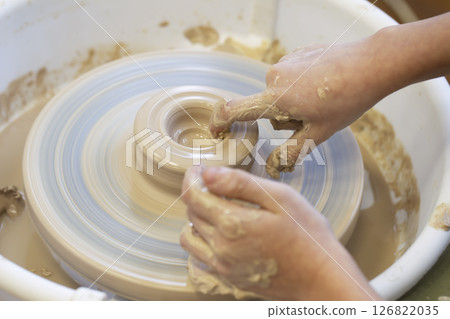 Close-up of a potter's hands with an item on a potter's wheel. Working with clay. Clay workshop. Craft training. 126822035