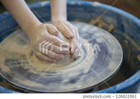 Close-up of a potter's hands with an item on a potter's wheel. Working with clay. Clay workshop. Craft training. 126822061