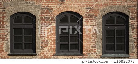 Brick wall of an old building with arched windows. Brick wall of an old building with arched windows. 126822075