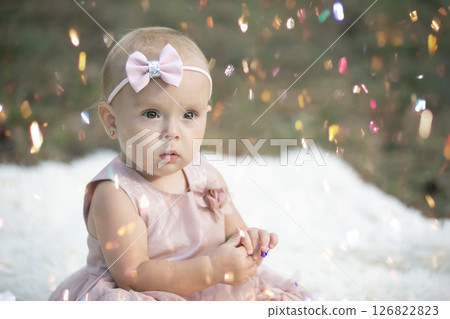 A funny little girl in a bright confetti. Child celebrates one year. Beautiful baby. 126822823