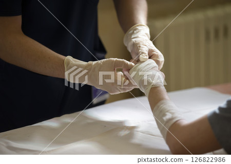 The doctor ties the patient's hand with a medical bandage. The doctor ties the patient's hand with a medical bandage. 126822986