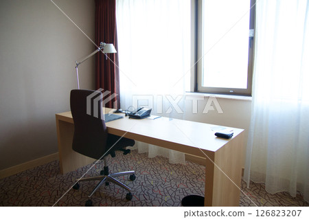 Mainz, Germany, July 7, 2017: Hotel Room Desk with Telephone, Lamp, and Chair by the Window 126823207