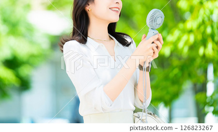 Woman cooling off with a handheld fan - summer heatstroke prevention Woman cooling off with a handheld fan - summer heatstroke prevention 126823267