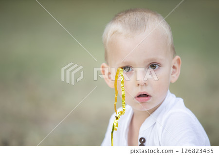 The face of a little surprised boy with a confetti ribbon. The face of a little surprised boy with a confetti ribbon. 126823435
