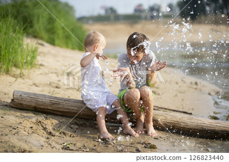 Water splashes are flying at children playing on the river bank. Water splashes are flying at children playing on the river bank. 126823440
