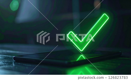 Bright green illuminated checkmark symbol emerging from smartphone screen in dark setting with reflective surface Bright green illuminated checkmark symbol emerging from smartphone screen in dark setting with reflective surface 126823783