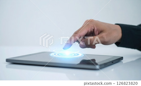 Close-up of hand touching futuristic hologram interface on tablet device with glowing circular pattern 126823820