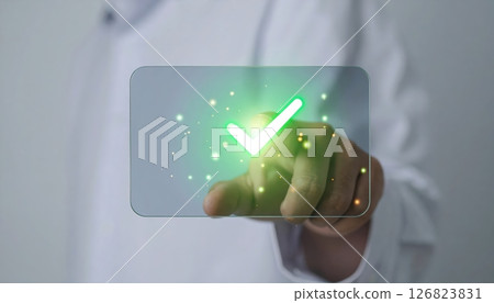 Medical professional in lab coat using a futuristic transparent touchscreen with green checkmark symbol Medical professional in lab coat using a futuristic transparent touchscreen with green checkmark symbol 126823831