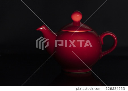 Teapot of red color of the classical form on a black background. 126824233