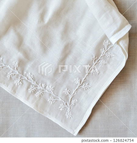 Embroidered white linen napkin on soft fabric. Minimal clean background for product presentation. 126824754