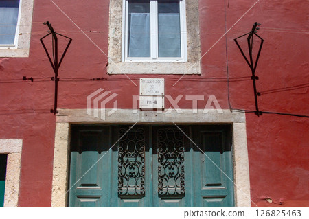 Building facade with a teal door and intricate ironwork in a red building. Building facade with a teal door and intricate ironwork in a red building. 126825463