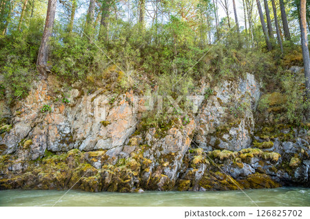 Rocky riverbanks of Katun river in Altai Russia close up. Detailed view of rugged cliffs and stones along mountain river shore. Rocky riverbanks of Katun river in Altai Russia close up. Detailed view of rugged cliffs and stones along mountain river shore. 126825702