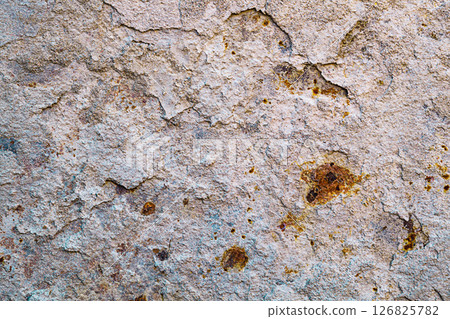 Background of a light beige metal wall from which layers of hardened cement mortar are peeling off, and the exposed areas are covered with brown, deep rust. Properties of structural materials 126825782