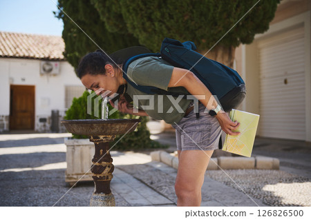 Traveler Exploring a Historic Spanish Village by Quenching Thirst at a Public Fountain 126826500