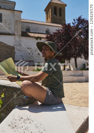 Traveler Exploring a Scenic Medieval Village With Map and Sun Hat 126826570