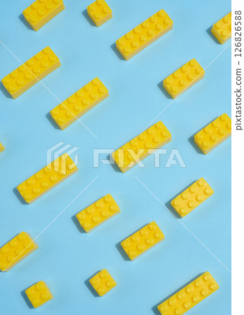 Scattered yellow plastic toy building bricks on a blue background. Play, construction, education or creative concept 126826588