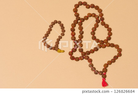 Top view of two strands of rudraksha beads, one of which is longer and has a red tassel, placed on a beige background Top view of two strands of rudraksha beads, one of which is longer and has a red tassel, placed on a beige background 126826684