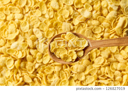 wooden spoon of delicious crispy corn flakes above tasty cornflakes as background. Top view. 126827019