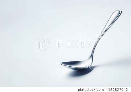 An elegant metal spoon ladle on a light background. Space for text. An elegant metal spoon ladle on a light background. Space for text. 126827042