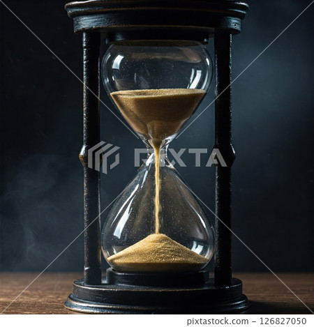 Hourglass on a wooden surface and a dark background. 126827050