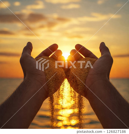 Hands letting go of the sand against the background of the sunset over the sea. Hands letting go of the sand against the background of the sunset over the sea. 126827186