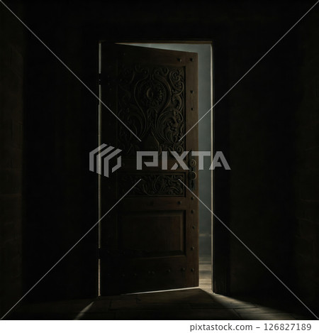 An old wooden door in the dark with a glimmer of light. 126827189