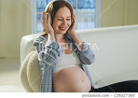 Pregnancy motherhood. Pregnant woman listening music for mother and unborn baby at home. Girl in headphones enjoying pregnancy listen music for relax healthy zen calm peace wellness, Maternity concept 126827360