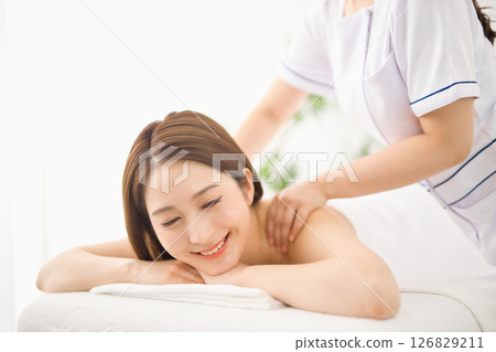 Young woman receiving a massage at an esthetic salon Young woman receiving a massage at an esthetic salon 126829211