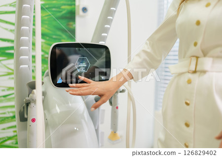 Close-up of medical female worker interacting with digital interface, adjusting settings on modern medical apparatus screen, enhancing patient care and treatment in medical clinical room. Close-up of medical female worker interacting with digital interface, adjusting settings on modern medical apparatus screen, enhancing patient care and treatment in medical clinical room. 126829402