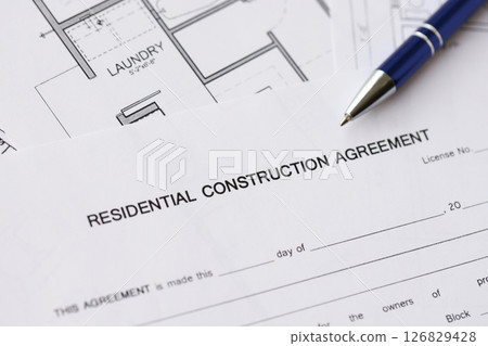Pen on residential construction agreement and planning blueprints of residential building project 126829428
