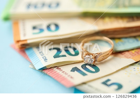 European union Euro money bills and coins with golden wedding ring on blue table 126829436